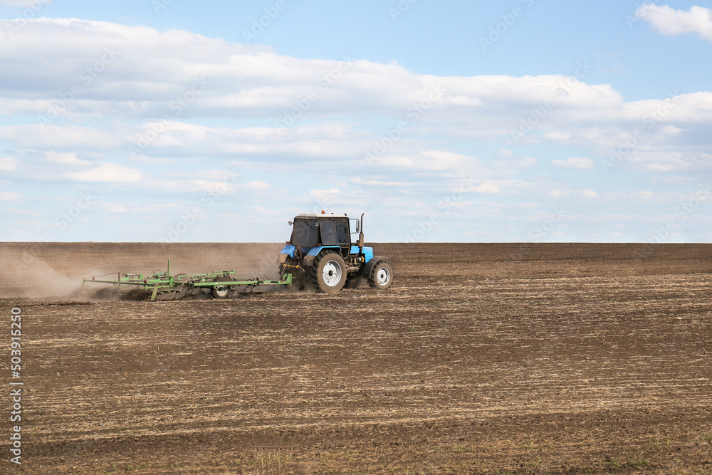 Obraz premium Tractor with planter cultivating field on sunny day. Agricultural industry