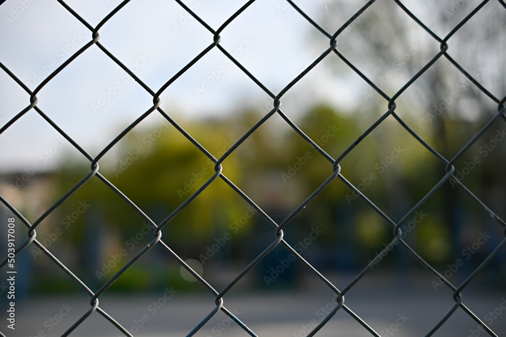 Metal mesh wire fence with blur basketball court background Metal mesh wire fence with blur basketball court background