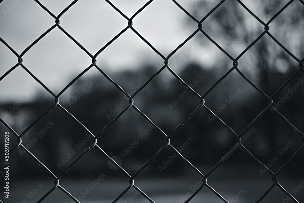 Fototapeta premium Metal mesh wire fence with blur basketball court background