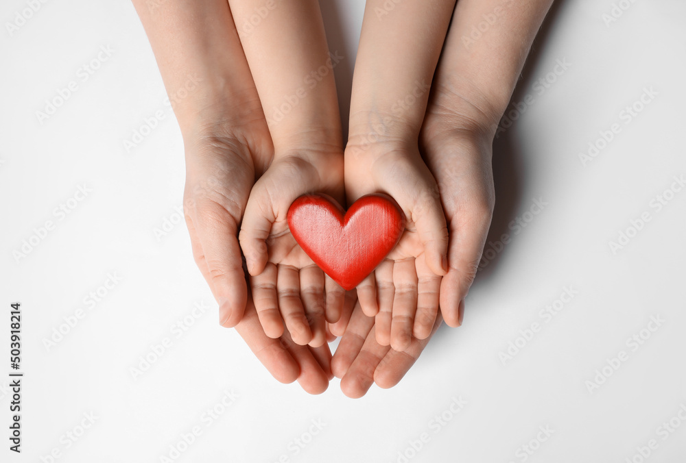 Fototapeta premium Woman and kid holding red heart in hands on white background, top view