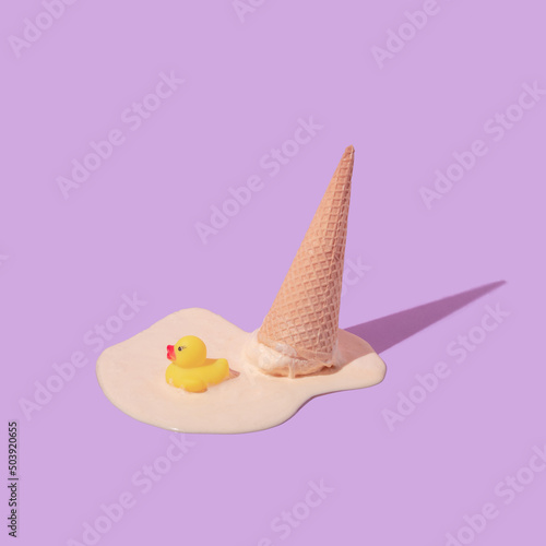 Summer creative layout with melting ice cream cone upside down and rubber duck toy on pastel purple background. 80s or 90s retro fashion aesthetic ice cream concept. Minimal summer idea. photo