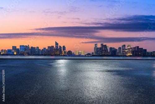 Empty asphalt road and modern city skyline with buildings in Hangzhou at sunrise, China.
