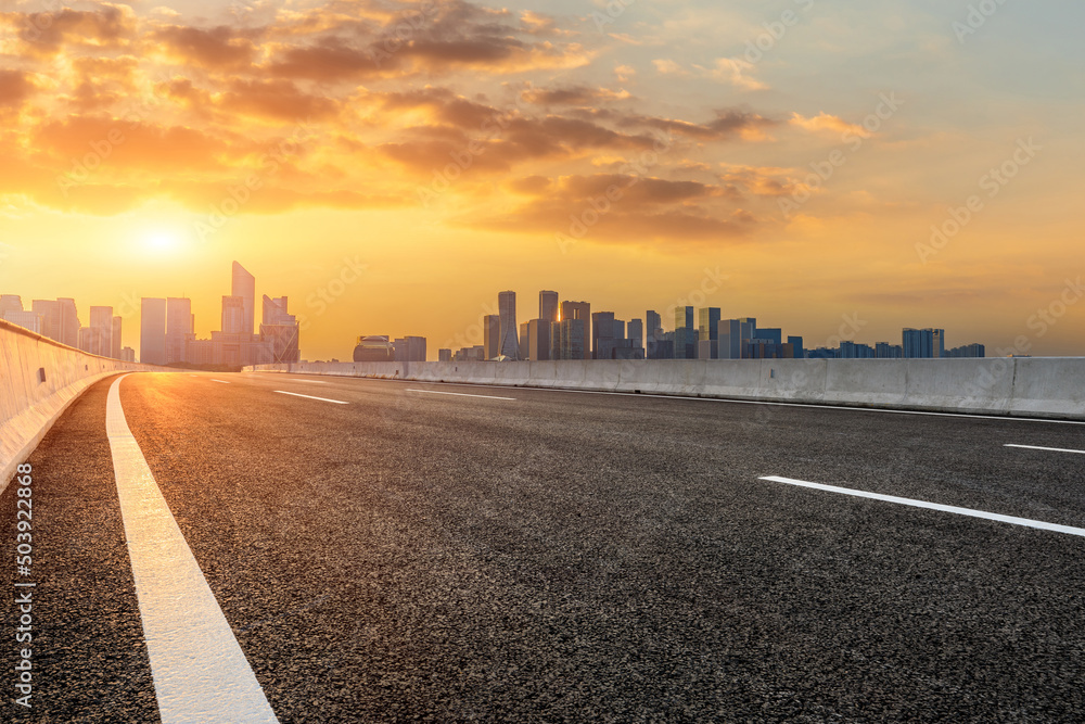 Asphalt road and modern city skyline with buildings in Hangzhou at sunset, China.