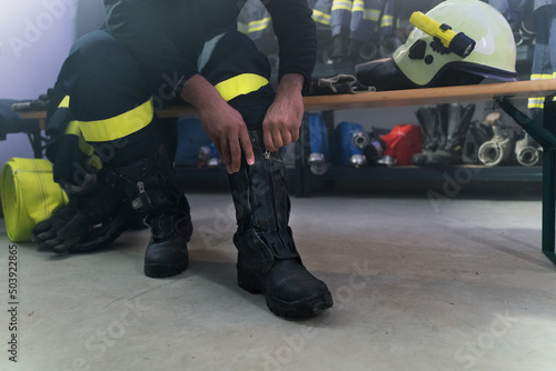 Bilde på lerret Lowsection of firefighter preparing for action in fire station at night