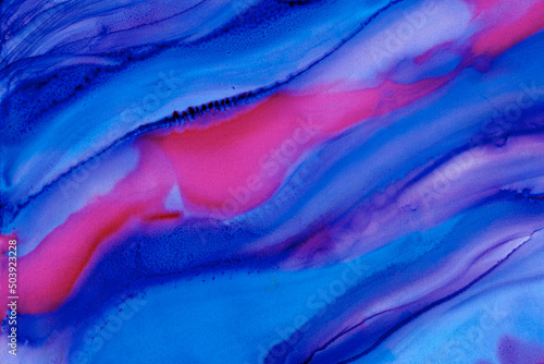 Abstract blue and pink alcohol ink background. Flowing colors of fuchsia and tones of blue ink in a diagonal direction
