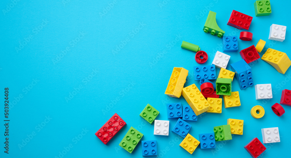 Scattered parts of a plastic children's designer, top view. Yellow blue background Scattered parts of a plastic children's designer, top view. Yellow blue background