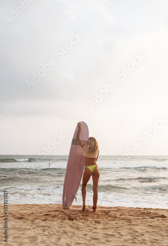 Kobieta z deską surfingową, surferka na tle oceanu na plaży.