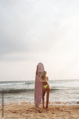 Kobieta z deską surfingową, surferka na tle oceanu na plaży.
