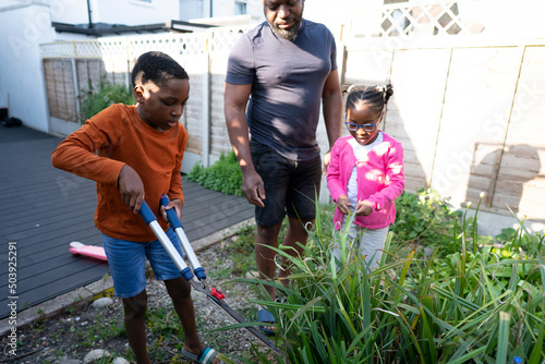 Father and children cutting grass in backyard photo