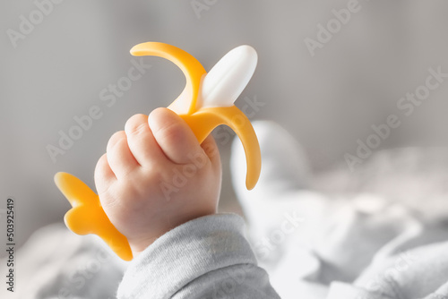 Fotografía a five-month-old baby holds banana teether in his hand, development and massage of the gums