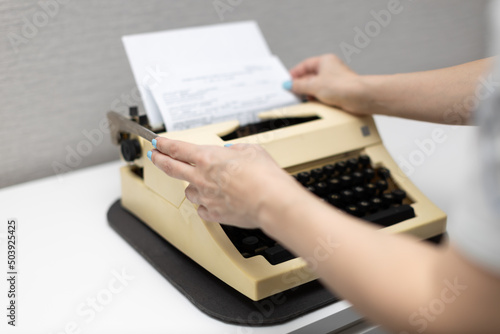 woman typing on a typewriter presses the carriage return lever photo