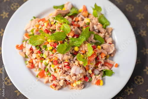 Spicy Tuna Salad with Chili, shallots, corn, mint leaves, carrot, lime and tomatoes cuisine in plate delicious favorite Thai food on table.