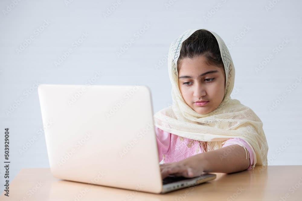 muslim girl in hijab using a laptop computer and online learning or working on the table muslim girl in hijab using a laptop computer and online learning or working on the table