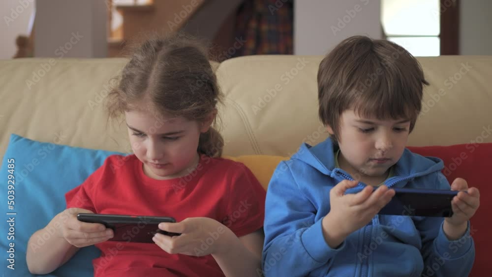 Children Playing Games In Phone at Home on Couch. Kids Playing Video ...