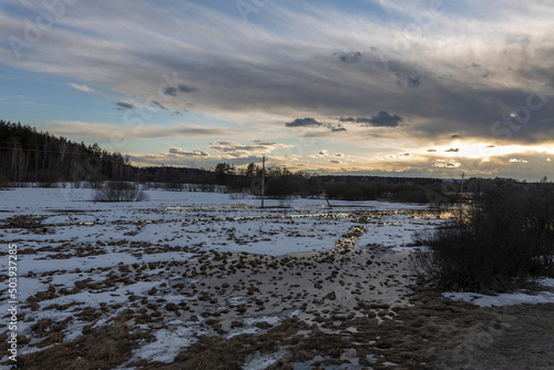 Epic spring landscape by the river. The flood of the river in early spring. A colorful sunset is reflected in the water. March evening landscape.