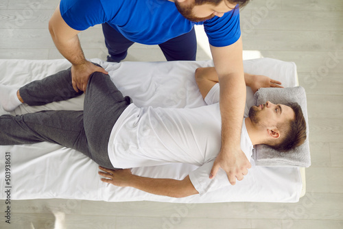 Top view of physiotherapist work relieve muscle strain or spasm for client lying on table in saloon. Masseur or therapist use manual massage techniques with patient at appointment. Physiotherapy.