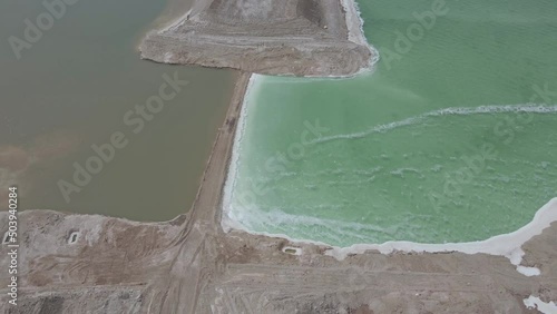 bird's eye view of a dike in the dead sea with the clear color differences of the water on both shores in jordan