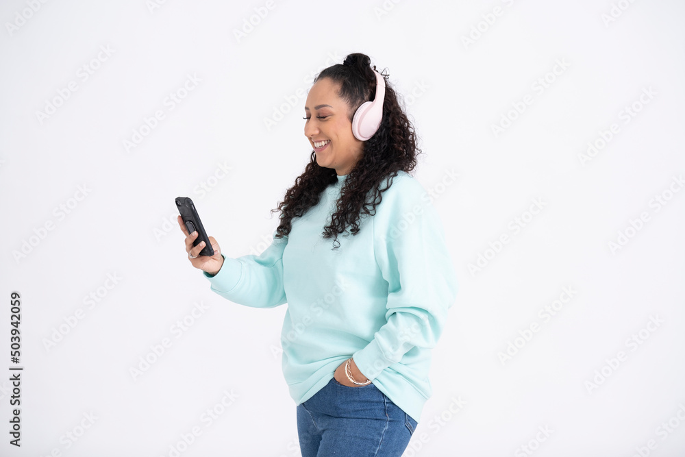 Studio shot of mid adult woman using smartphone and headphones Studio shot of mid adult woman using smartphone and headphones