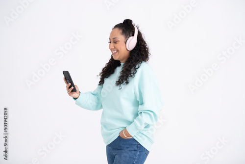 Studio shot of mid adult woman using smartphone and headphones