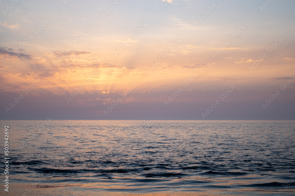 Sunset over the sea. Sunbeams through the clouds.