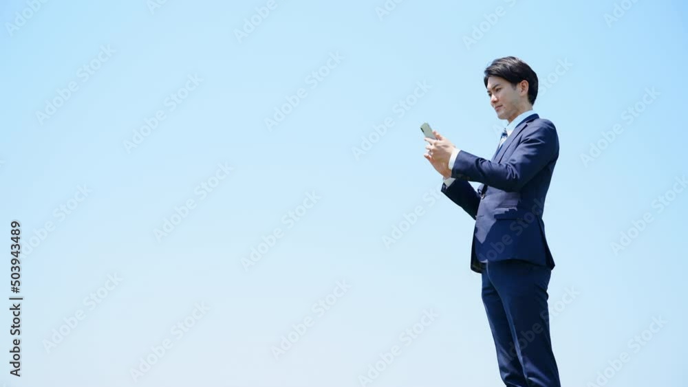 スマートフォンを誘う擦る若いビジネスマン ビジネスイメージ スマートフォンを誘う擦る若いビジネスマン ビジネスイメージ