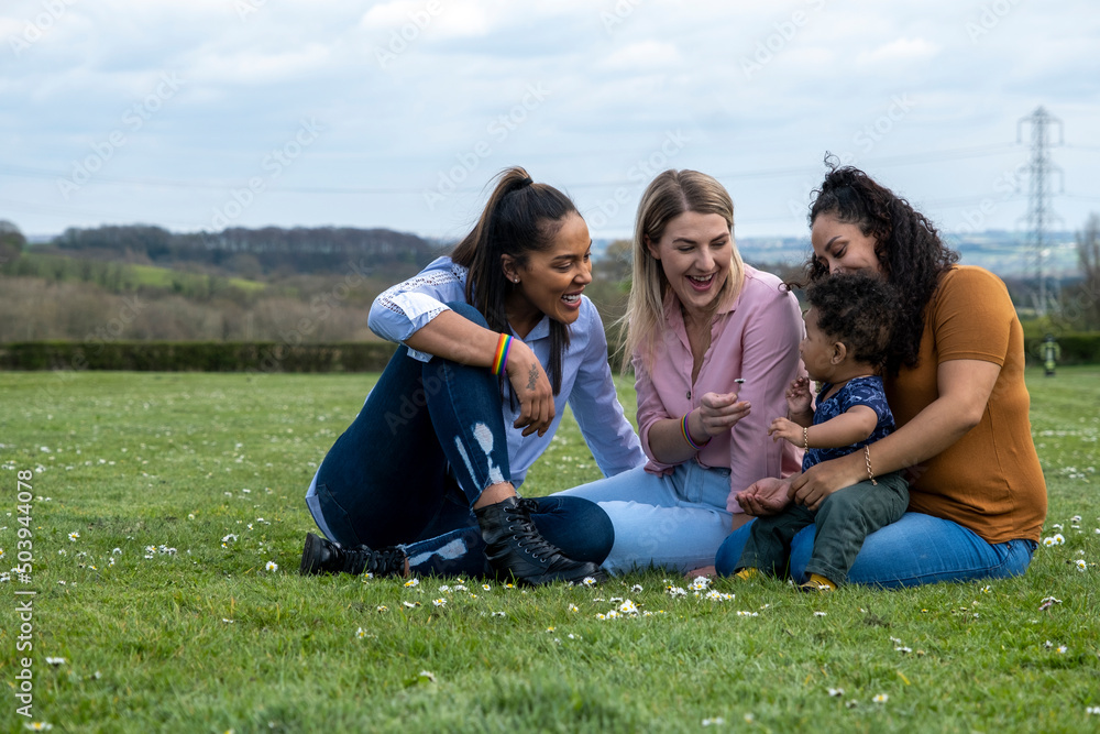Women sitting on grass with baby boy Women sitting on grass with baby boy