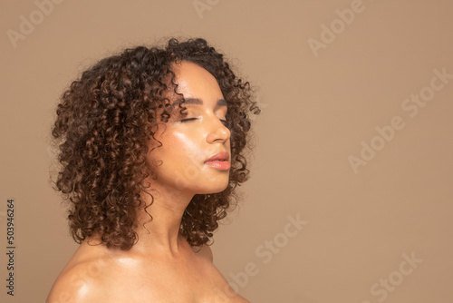 Studio shot of woman with curly hair and eyes closed
