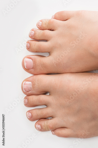 Female feet with soft skin and french pedicure on white background
