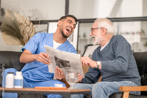 Fotografie Caregiver and an aged man laughing at a news item