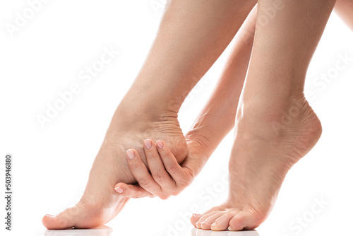 Woman gently touching soft skin of her heel. Female feet on white background. photo