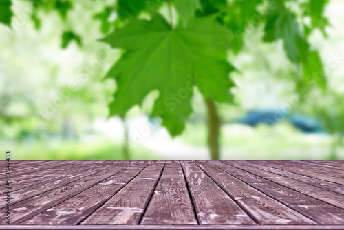 Mockup. Empty wooden deck table with foliage bokeh background.