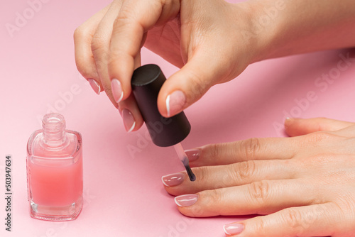 Female hand with beautiful french manicure applying pink nail polish