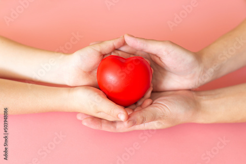 Adult and child hands holding red heart, health care love, give, hope and family concept, world heart day,world health day