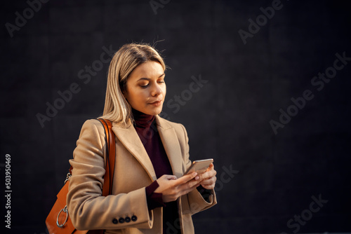 A woman using her phone outside on cold weather.