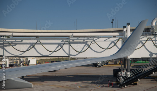 airplane wing in front of hoses cables and lines hanging or draped on support wall creating wave like shapes and shadows horizontal format room for type content or logo  travel backdrop or background  photo