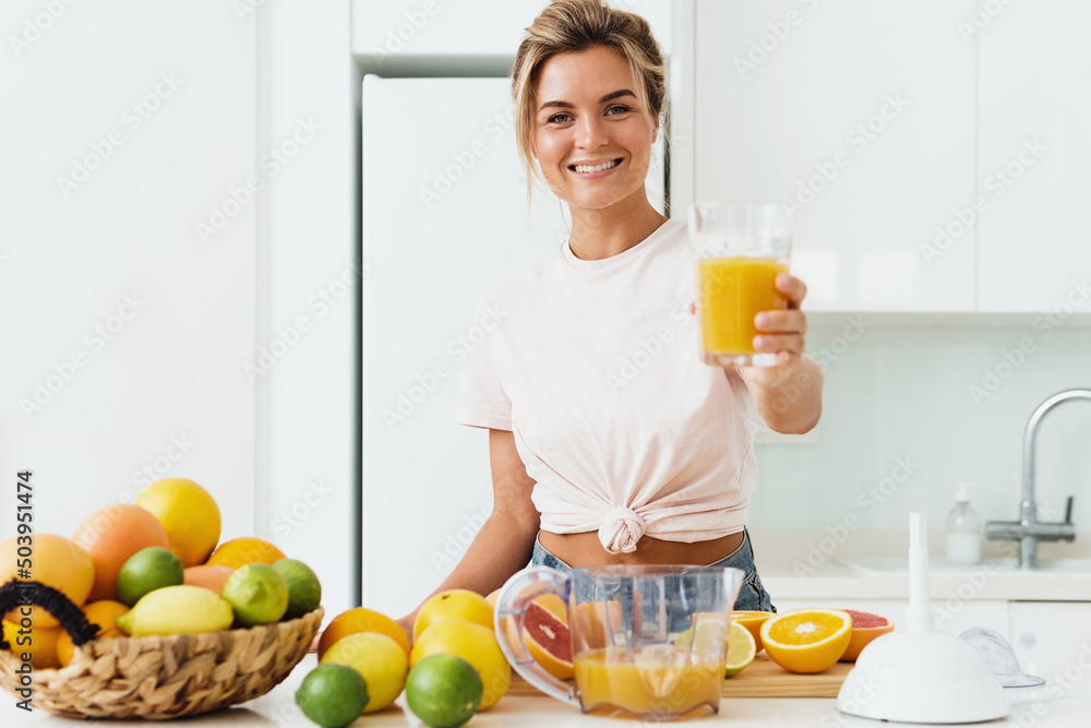 Young cheerful woman with big glass of fresh orange juice Young cheerful woman with big glass of fresh orange juice