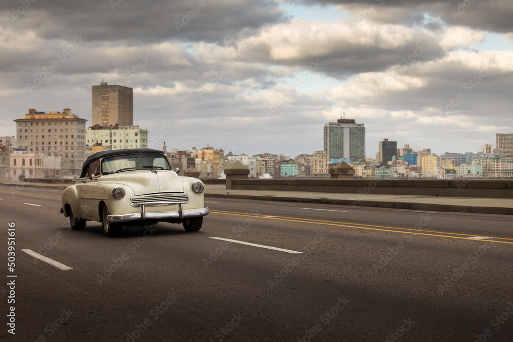 Fototapeta premium Old car on Malecon street of Havana with storm clouds in background. Cuba