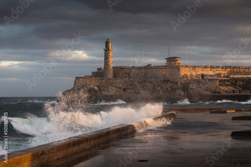Big waves on Malecon streets during sunrise with storm clouds in background. Havana, Cuba