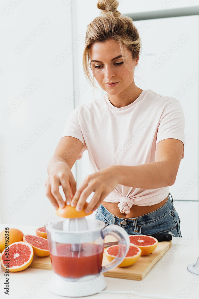 Woman with a lot of citrus fruits during fresh grapefruit juice preparation at home
