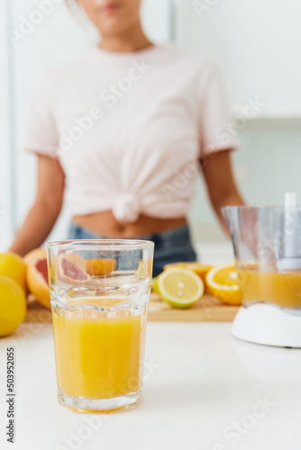 Glass of orange juice and citrus juicer on kitchen table
