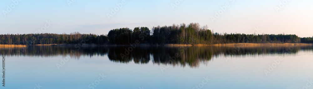 Obraz premium Long panorama view with lake reflecting forest on evening