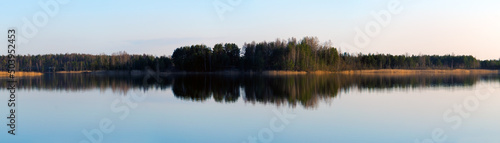 Long panorama view with lake reflecting forest on evening