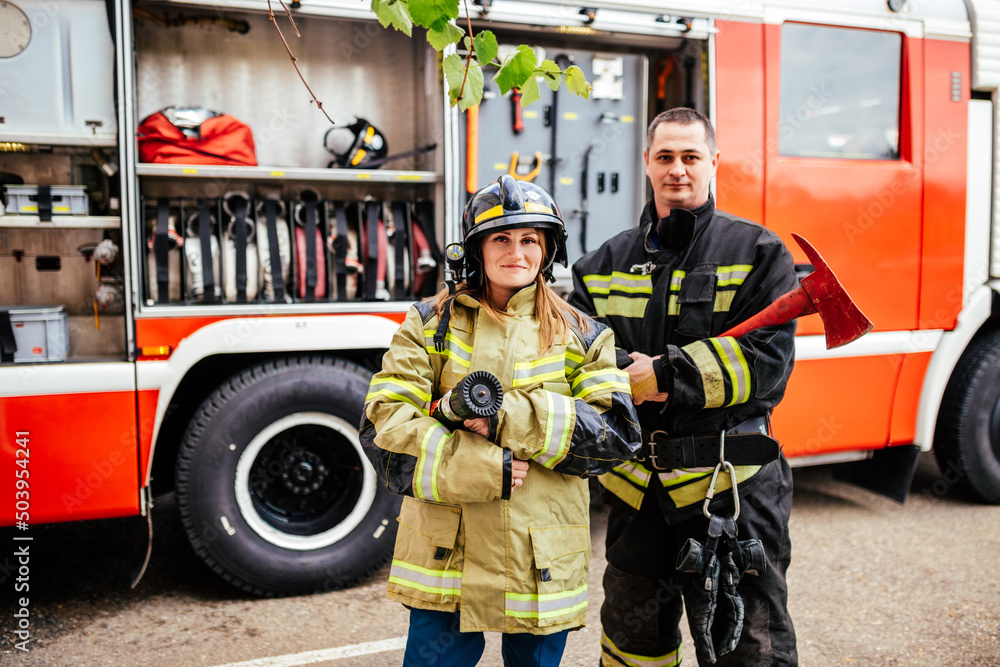 custom made wallpaper toronto digitalFirefighters woman and man in helmets looking at camera near fire truck. Protection, rescue from danger. Fire station