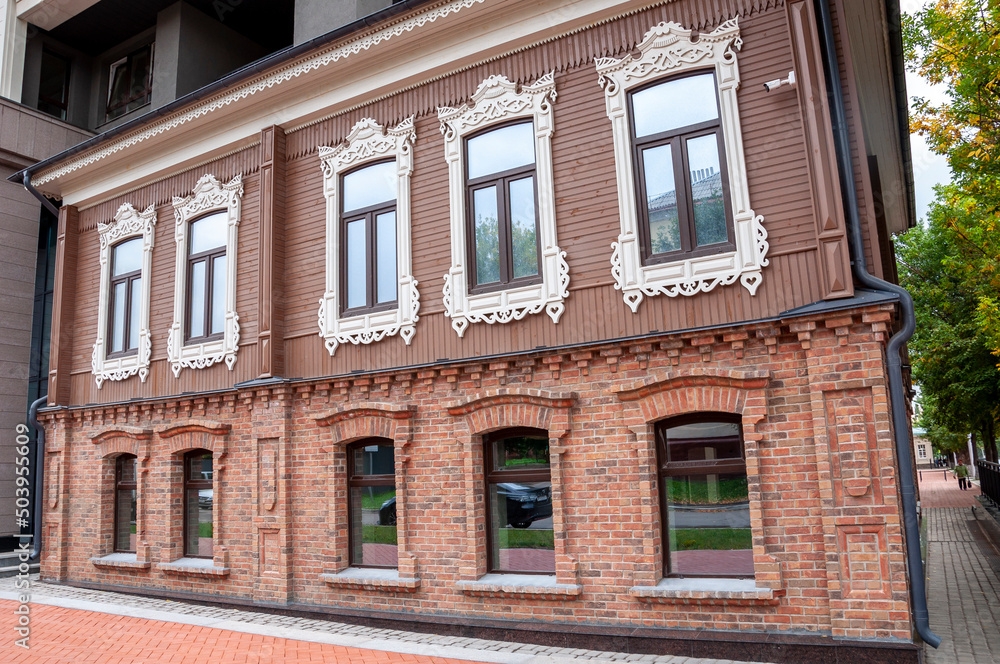 Obraz premium Ancient historical profitable carved houses made of wood are located on the streets of the modern city