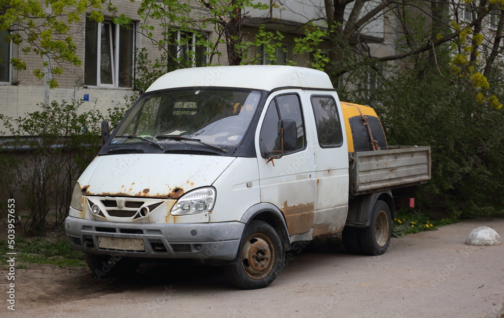 Small Russian truck with white cab and open body, Dybenko Street, St. Petersburg, Russia, May 2022