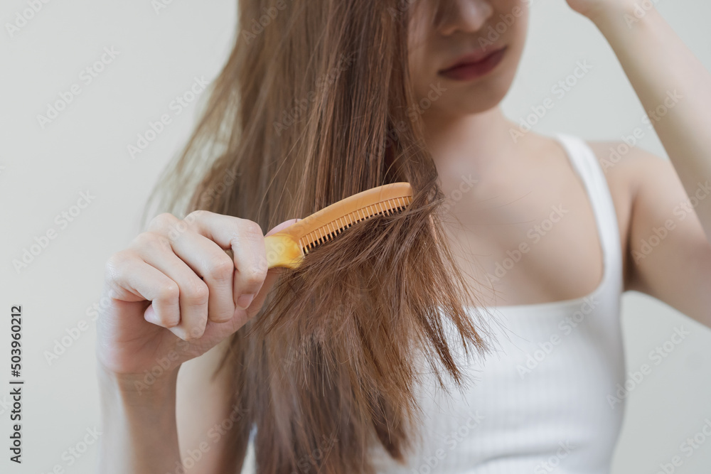 Damaged Hair, frustrated asian young woman, girl hand in holding brush splitting ends messy while combing hair, unbrushed dry long hair. Health care beauty, portrait isolated on white background. Damaged Hair, frustrated asian young woman, girl hand in holding brush splitting ends messy while combing hair, unbrushed dry long hair. Health care beauty, portrait isolated on white background.