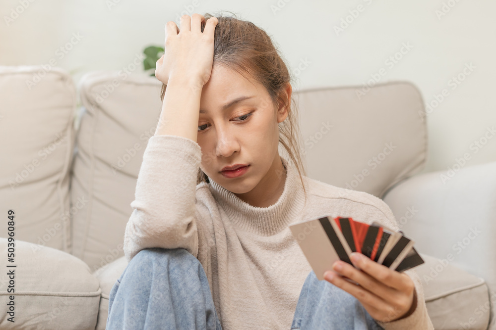 Financial owe asian young woman, girl sitting suffer, stressed and confused, sitting and holding many credit card, no money to pay expense, mortgage or loan. Debt, bankruptcy or bankruptcy concept. Financial owe asian young woman, girl sitting suffer, stressed and confused, sitting and holding many credit card, no money to pay expense, mortgage or loan. Debt, bankruptcy or bankruptcy concept.