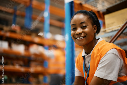 Happy African American female worker at distribution warehouse looking at camera.