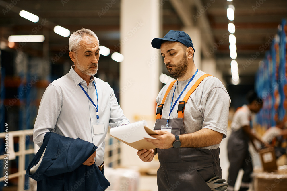 Mature inspector and warehouse worker going through paperwork at distribution warehouse. Mature inspector and warehouse worker going through paperwork at distribution warehouse.