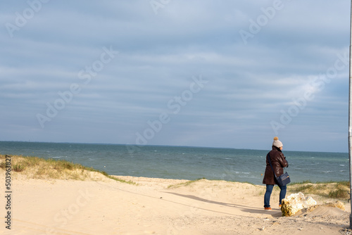 Rear view of a woman standing on beach looking out to sea in winter, Ile de Re, Rivedoux et Ars en Re, Charente Maritime, France photo